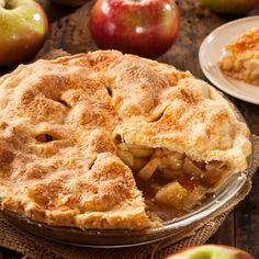 an apple pie on a wooden table with two plates and forks