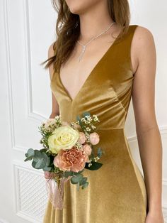 a woman in a gold dress holding a flower bouquet