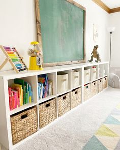 a chalkboard and bookshelf with baskets in front of it