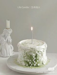 a white cake sitting on top of a plate next to a candle