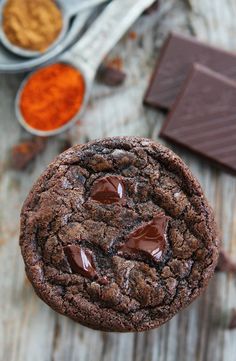 a chocolate cookie on a wooden table next to some spices