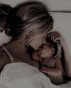 a woman laying in bed next to a baby with her head on her mother's chest