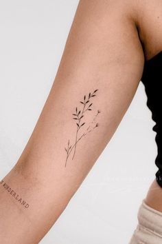 a woman's arm with a small black flower tattoo on the left side of her arm