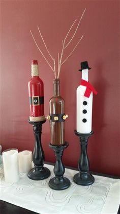 three wine bottles are sitting on a table next to each other, one has a snowman and the other is a bottle