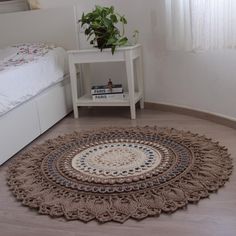 a white bed sitting next to a small table with a plant on top of it