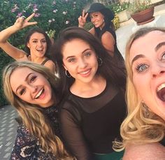 four women posing for the camera with their hands in the air and one holding her mouth open