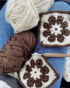 crocheted grannys and balls of yarn sitting on top of a blue blanket