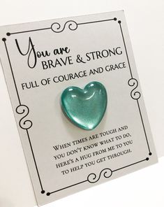 a green heart shaped brooch sitting on top of a piece of paper with the words you are brave and strong