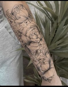 a woman's arm with black and white flowers on the left side of her arm