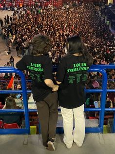 two people standing in front of an audience at a concert with their arms around each other