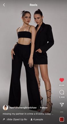 two women standing next to each other in black outfits