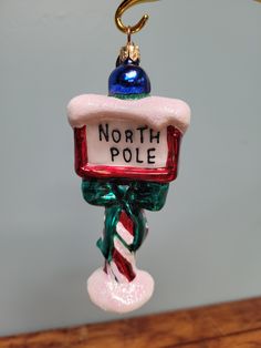 a glass ornament with a north pole sign on it's back hanging from a hook