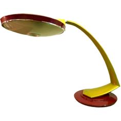 a red and yellow desk lamp on a white background with the light turned off to show it's dim lighting