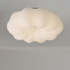 a large white light fixture hanging from the ceiling in a room with gray walls and flooring