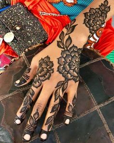 a woman's hand with hennap and flowers on it, next to other accessories