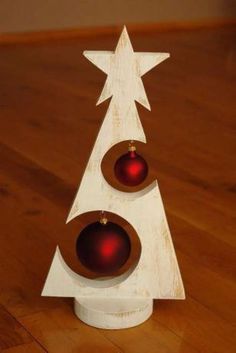 a wooden christmas tree with two red ornaments on it's top and an ornament in the shape of a star