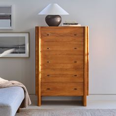 a wooden dresser sitting next to a bed in a room with a lamp on top of it