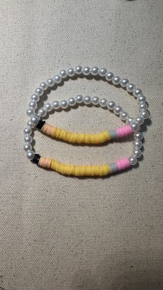 two bracelets with pearls and beads are on the floor