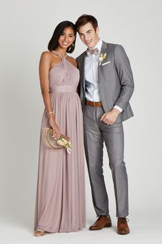 a young man and woman in formal wear posing for a photo together, dressed in grey suits