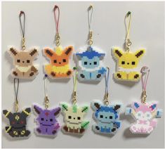 six pixelated pokemon key chains hanging on a white wall, each with different colors and sizes