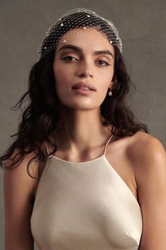 a woman wearing a white dress and headpiece with pearls on it's head