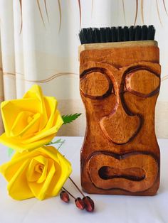 a wooden vase sitting next to a yellow rose