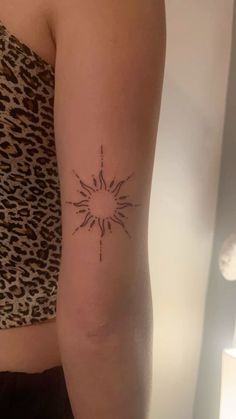 a woman's arm with a small sun tattoo on the back of her left arm