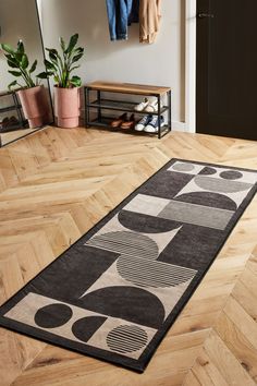 a black and white rug on the floor in front of a coat rack with shoes