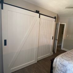 an open sliding door in a bedroom next to a bed with a white comforter