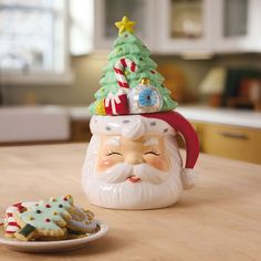 a santa claus cookie jar with cookies on the table next to it and a plate of cookies