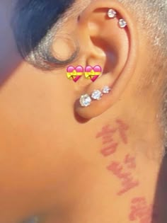 the back of a woman's ear with three hearts on it