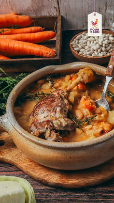 a bowl filled with stew and carrots on top of a wooden table next to other vegetables