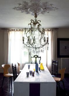 a chandelier hangs from the ceiling above a dining room table with four chairs