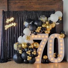 a large balloon arch with the number seventy on it in front of a black and white backdrop