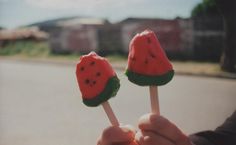 two watermelon lollipops being held by someone