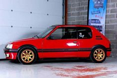 a red car parked in front of a brick wall next to a white garage door