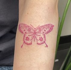 a small pink butterfly tattoo on the arm