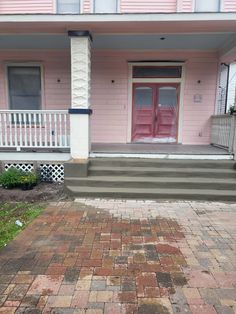 a pink house with steps leading up to the front door