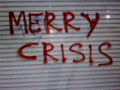 the words merry crisss written in red spray paint on a closed door with roller shutters