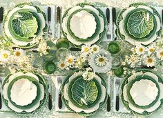 an overhead view of a table set with plates and silverware, surrounded by daisies