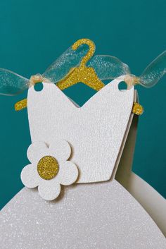 a close up of a white dress with a flower on the front and gold accents