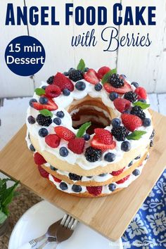 an angel food cake with berries is on a cutting board and ready to be eaten