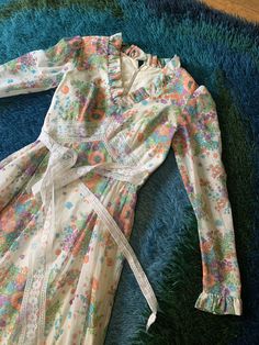 "Probably one of the best examples of a 70's prairie dress I've seen, purely based on the floral print alone! I just love the colors. Attached lace sash (linger on one side than the other) and multi-layer skirt. Fully lined. Does need a soak/dry clean as it has been in storage for decades. Reflected in price. Bust: 32\" Waist: 24\" Hips: free Length: 56\" Model is 5'7\" and 115 lbs with measurements of 32x24x34. Buy with confidence as all photos are taken in natural lighting." Bohemian Fitted Prairie Dress With Floral Print, Multicolor Floral Print Cottagecore Dress, Cottagecore Multicolor Floral Print Dress, Spring Floral Print Fitted Prairie Dress, Spring Prairie Dress With Ruffles, 1970s Retro Print Spring Dress, Multicolor 1970s Spring Dresses, Retro Fitted White Prairie Dress, Hippie Ruffle Dresses For Spring