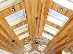 a living room filled with lots of furniture next to a ceiling mounted light fixture on a wood paneled wall