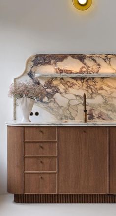 a bathroom vanity with marble counter top and wooden cabinetry, along with a gold light fixture