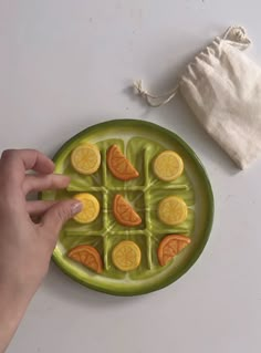 a green plate topped with orange slices on top of a white table next to a drawstring bag