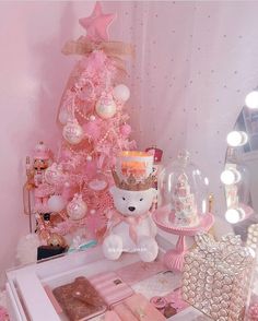 a pink christmas tree with lots of ornaments and decorations on it's sides, next to a white teddy bear