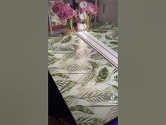 a table with flowers and vases on it in front of a mirror that is lit up