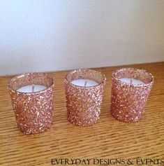 three glitter candles sitting on top of a wooden table