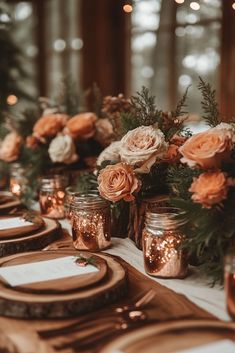 the table is set with candles, plates and vases filled with flowers on it